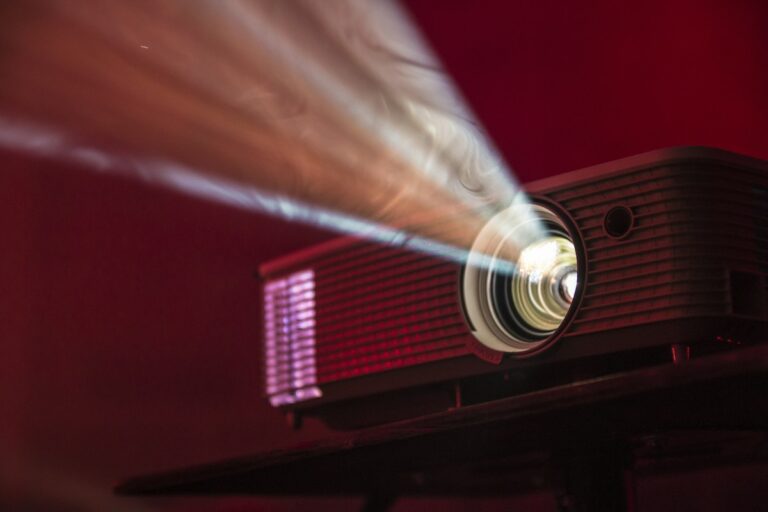 Vintage cinema projector lens throwing widescreen light across a classic movie auditorium