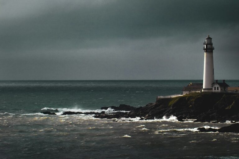 Historic granite lighthouse tower perched on rugged oceanic cliffs battling Atlantic coastal gales